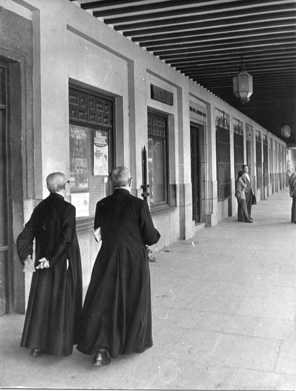 Dos sacerdotes paseando por los soportales de la plaza de Zocodover. [Imagen]